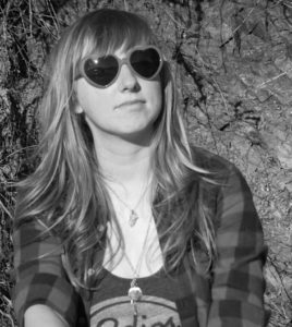 Black and white photo of Ainslie Greig in heartshaped sunglasses